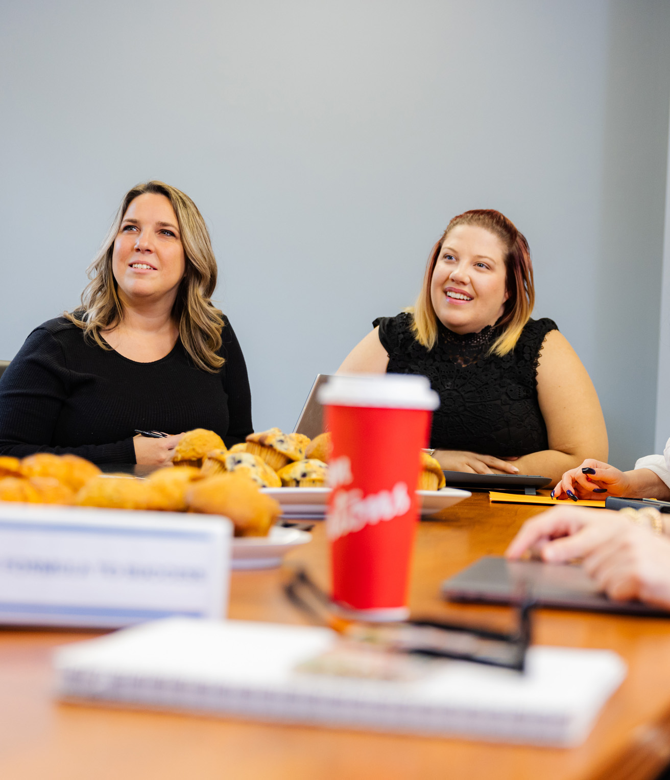 Jennifer and Kelsey at AnswerPlus sitting in a meeting with pastries and Tim Horton's coffee