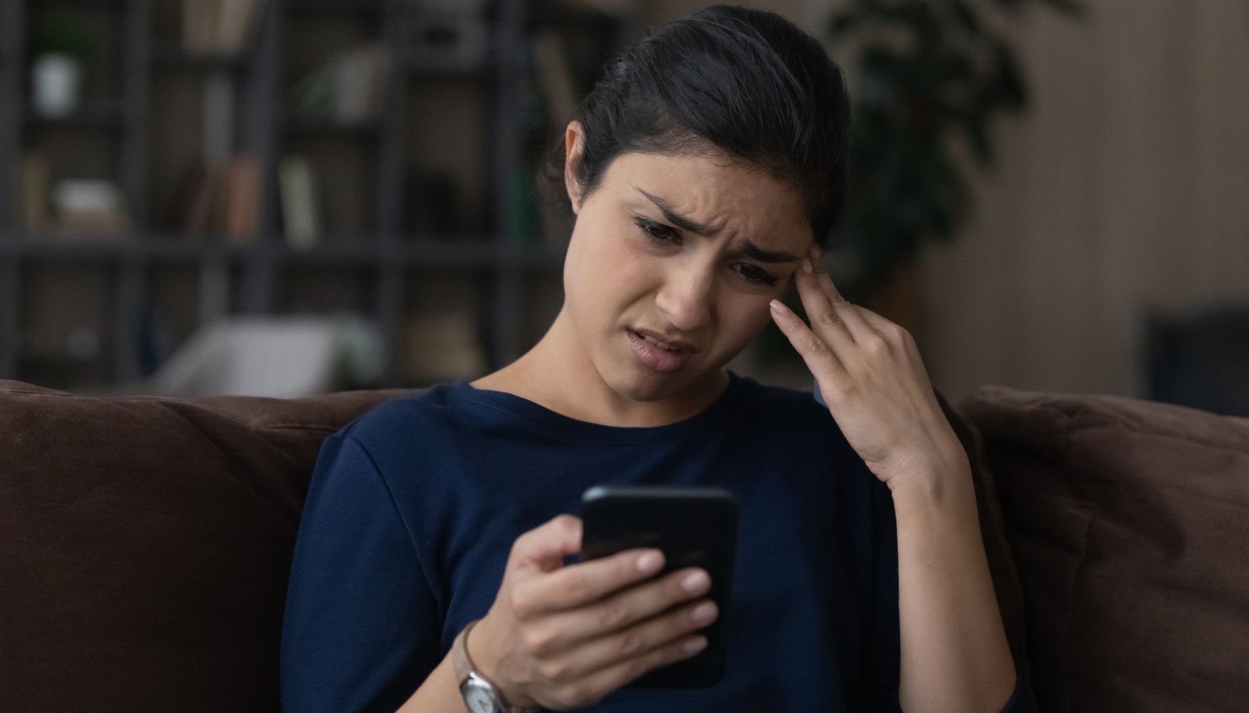 unhappy biracial woman starting at important missed call on cell phone screen
