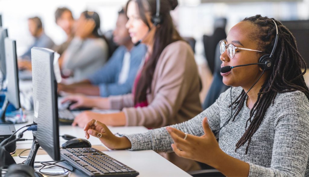 customer service representative using headset working at computer in call center environment
